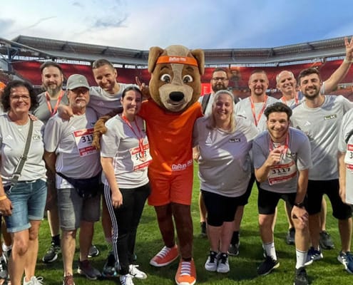 LK Metall employees pose with the B2Run mascot in the Max Morlock Stadium